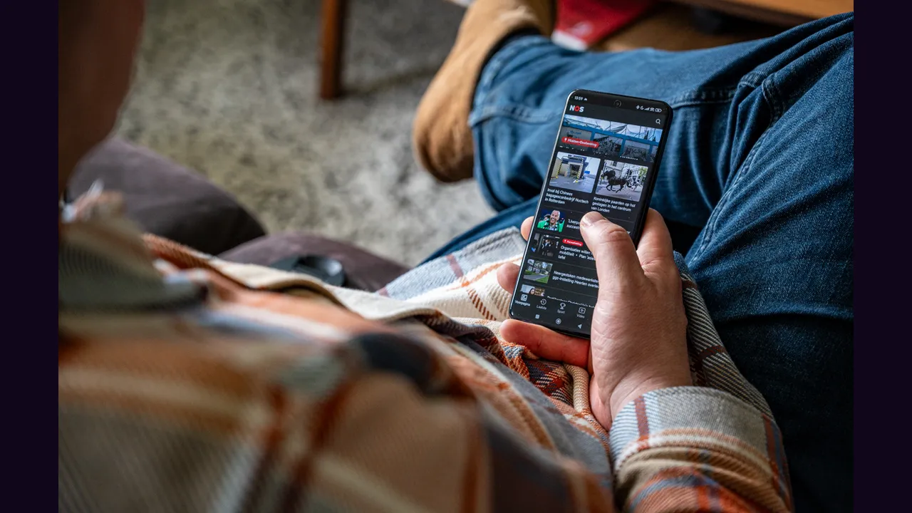 A person holding an Android phone showing a video app